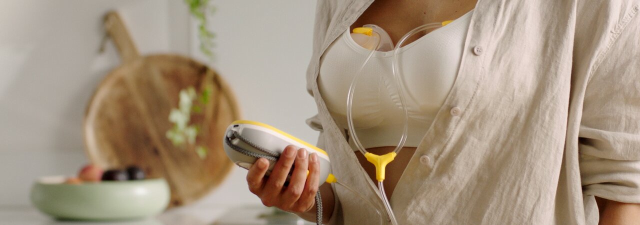 Mom wearing her Medela Freestyle™ Hands-free double electric wearable breast pump showing how easily the collection cups fit inside her bra