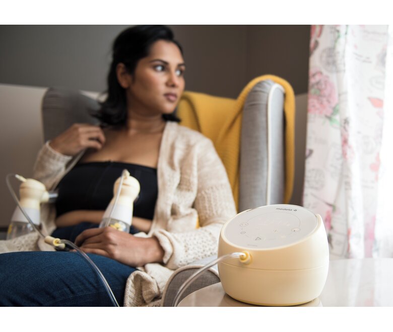 Mom sitting in chair and double pumping using her Medela Sonata® Smart double electric breast pump