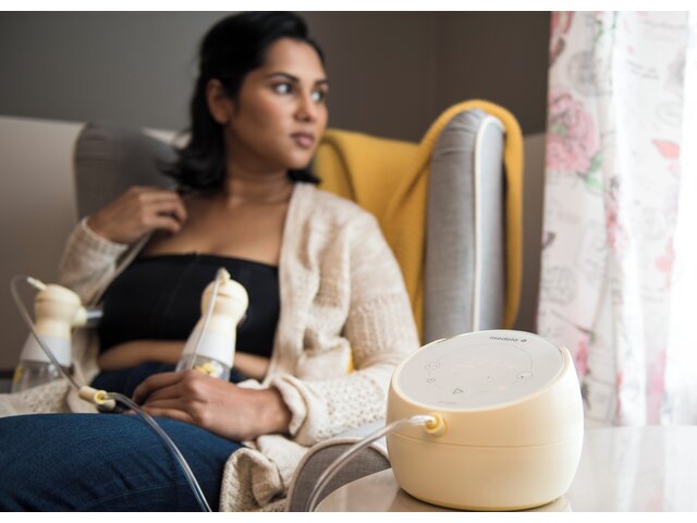 Mom sitting in chair and double pumping using her Medela Sonata® Smart double electric breast pump