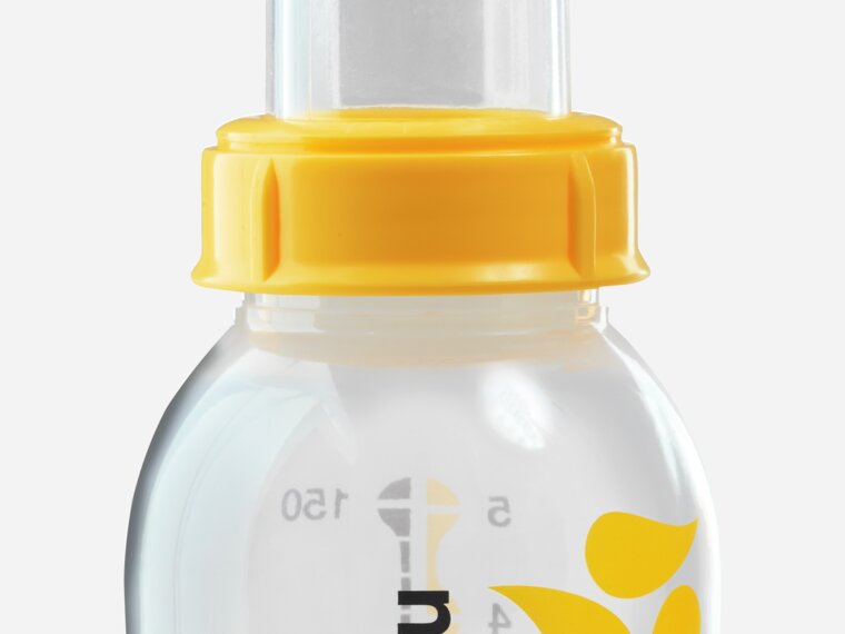 An advanced cup feeder, the Medela SoftCup™. It is connected to a reusable Medela breast milk storage bottle.