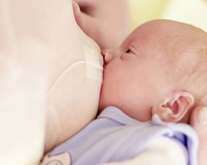 A mom breastfeeding her baby and supplementing the diet using Medela's Supplemental Nursing System™ (SNS).