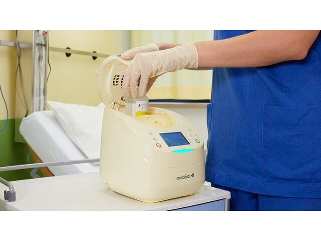 A nurse in the NICU prepares a breast milk storage container with the Medela Calesca warming and thawing device.