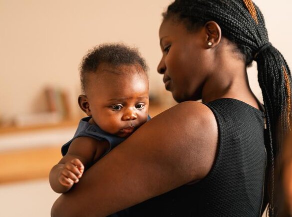 Eine Mutter hält ihr Baby zu Hause im Arm.