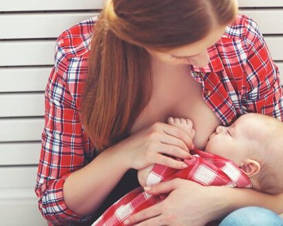 A young mother nurses her baby while looking down.