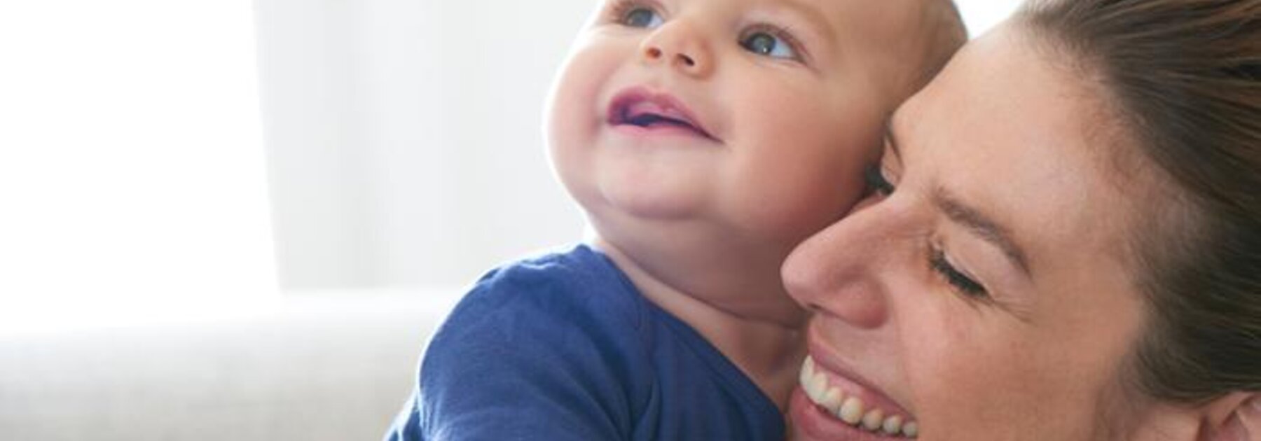 A mother holds her baby while they both laugh.
