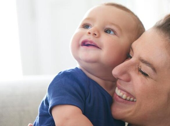 A mother holds her baby while they both laugh.