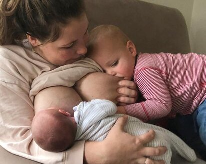 Two babies are breastfed in tandem by their mother.