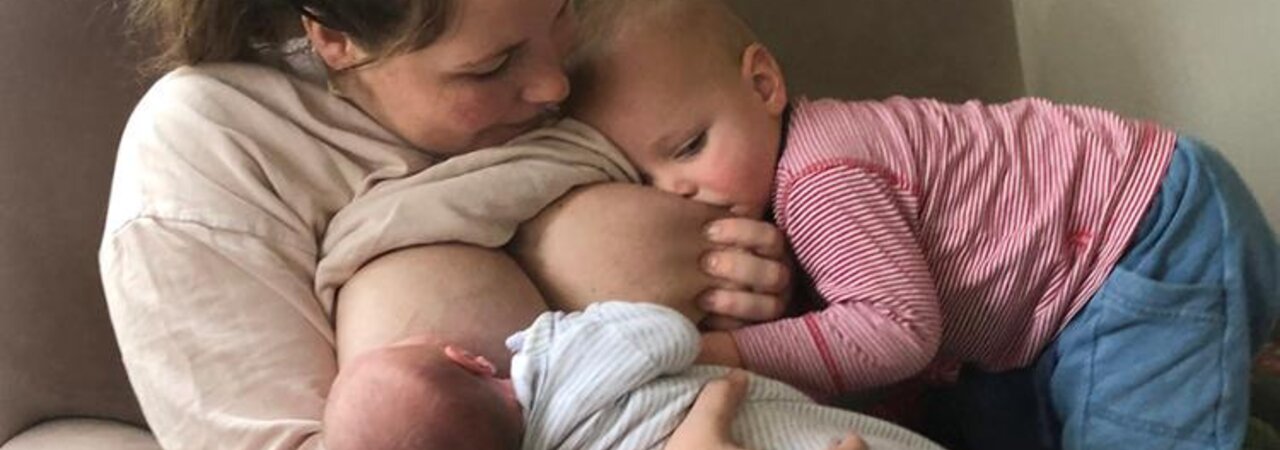 Two babies are breastfed in tandem by their mother.