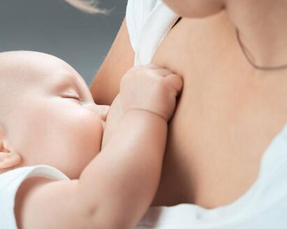 Close-up of a sleeping baby being breastfed.