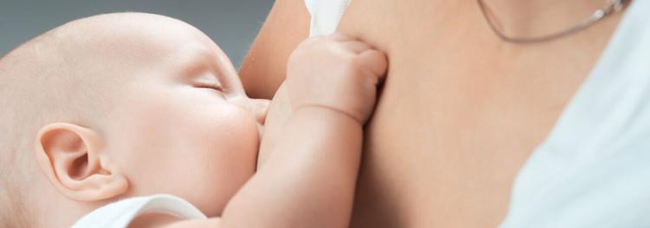 Close-up of a sleeping baby being breastfed.