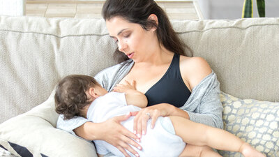 A mother breastfeeding her baby while wearing a Medela maternity bra.