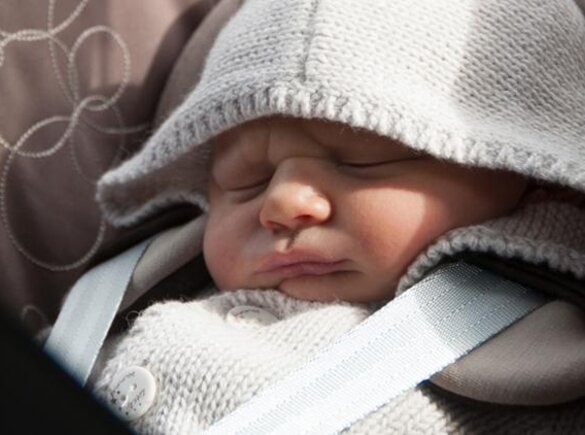 Een baby zit vast in een autostoeltje.