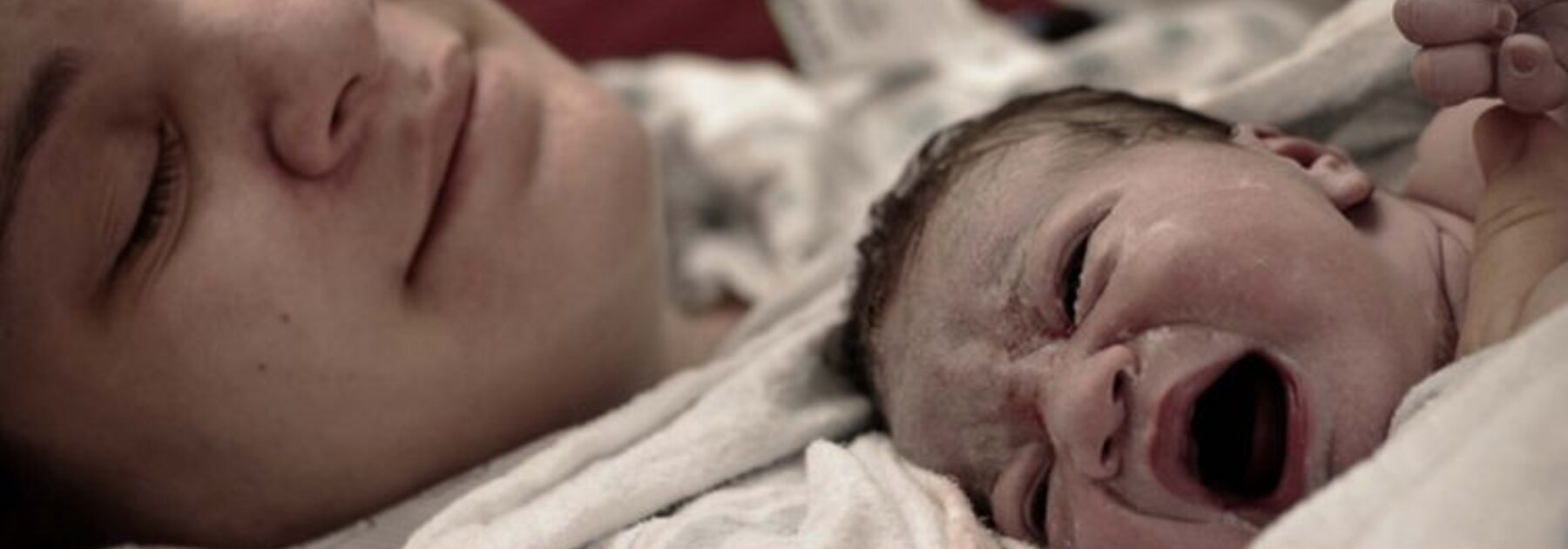 Een moeder ligt met haar pasgeboren baby op haar borst vlak na de bevalling.