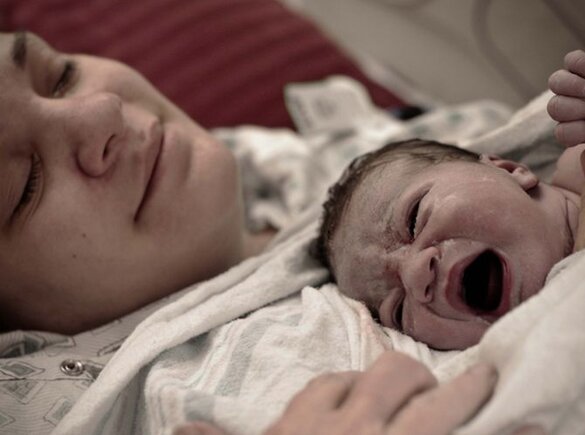 Een moeder ligt met haar pasgeboren baby op haar borst vlak na de bevalling.