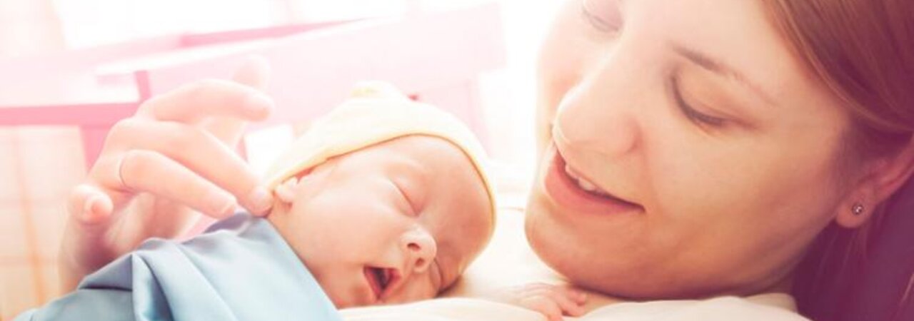 Woman holding newborn on her chest in a soft focus