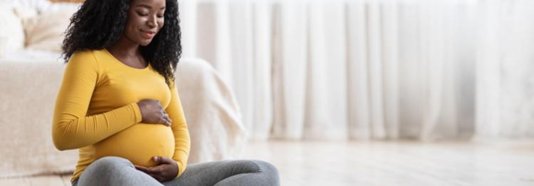 Zwangere moeder zittend op een yogamat.