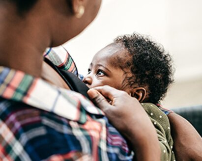 A mom breastfeeding her baby while it faces her.