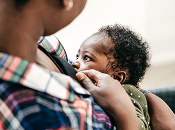 Een moeder die haar baby borstvoeding geeft terwijl hij naar haar kijkt.