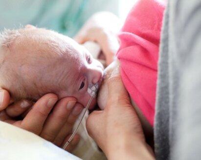 A mother breastfeeds her premature baby.