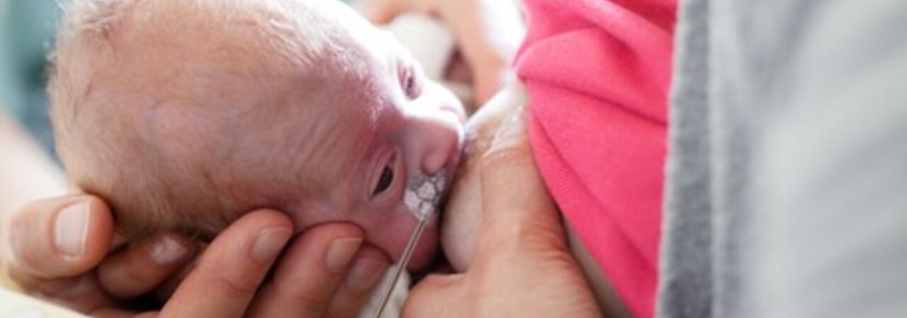 A mother breastfeeds her premature baby.