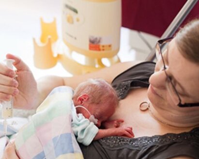 A mom sits with her preemie on her chest.