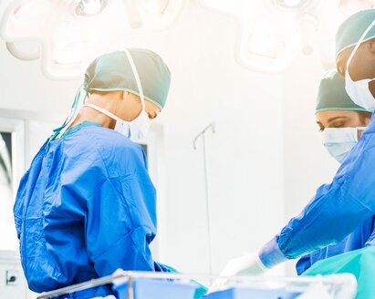 Doctors in an operating room with a patient. The room can be seen from the center to the ceiling, the patient himself is not depicted.