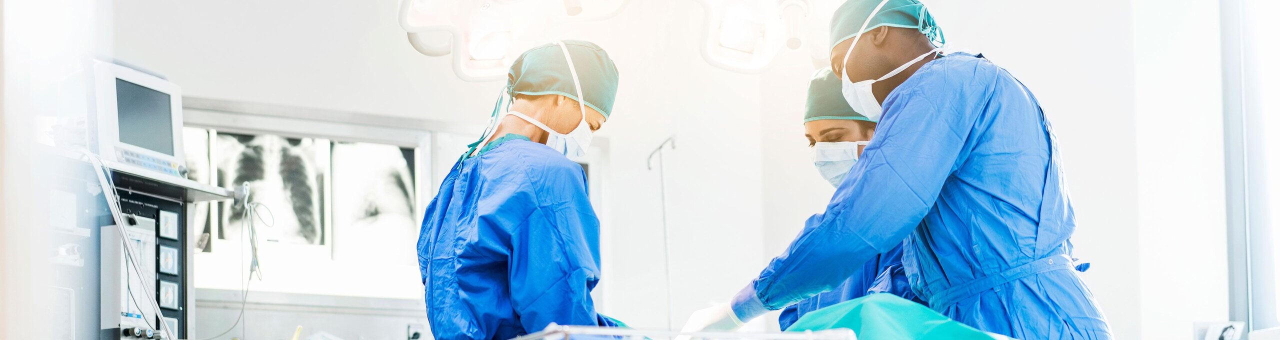 Doctors in an operating room with a patient. The room can be seen from the center to the ceiling, the patient himself is not depicted.