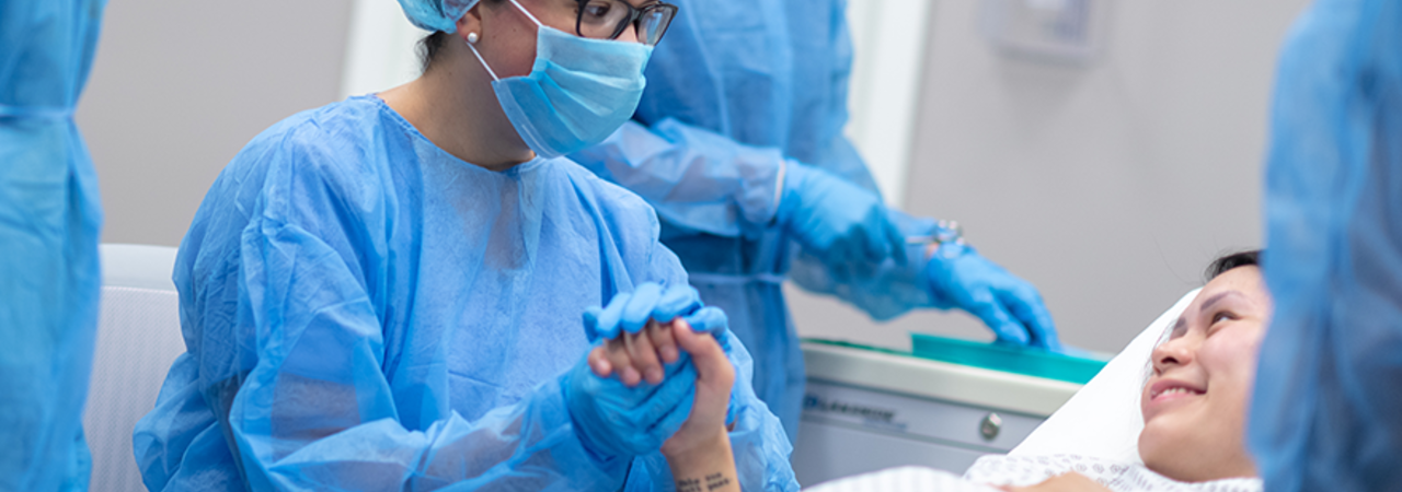 Operating room with doctor holding pregnant mother's hand