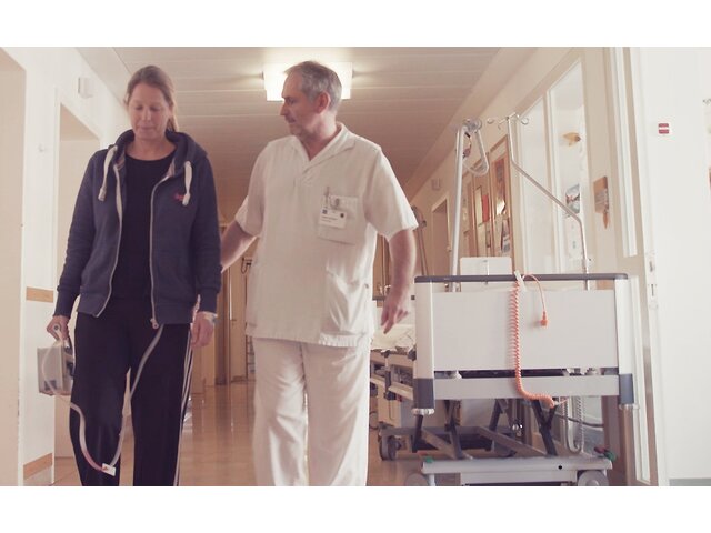 A healthcare professional walks with a patient carrying the portable Thopaz+ digital chest drainage and monitoring system.