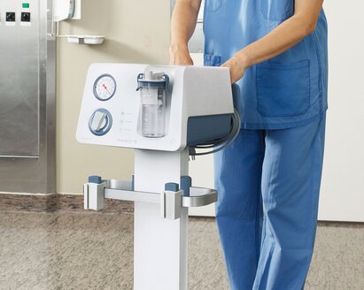 Surgical room showing a nurse push a Medela Dominant Suction Pump