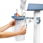 A person's hands release the Clamp Holder that attaches a disposable suction jar to a standard rail, for use with a Medela surgical suction pump.