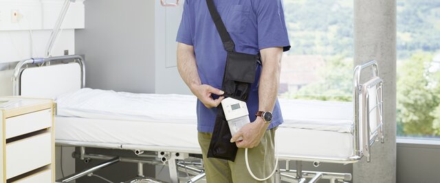 A man takes a Medela Invia Motion NPWT device out of its' carrying case, in a hospital.