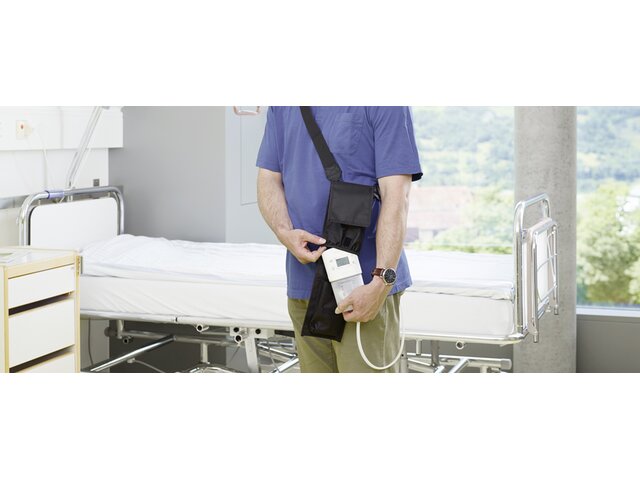 A man takes a Medela Invia Motion NPWT device out of its' carrying case, in a hospital.