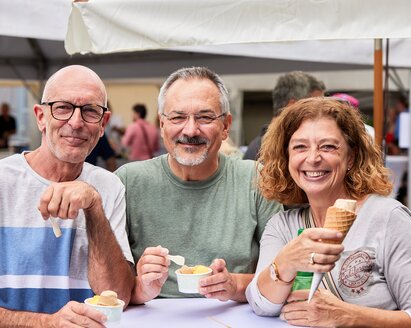 Two men and a woman enjoying ice cream together.