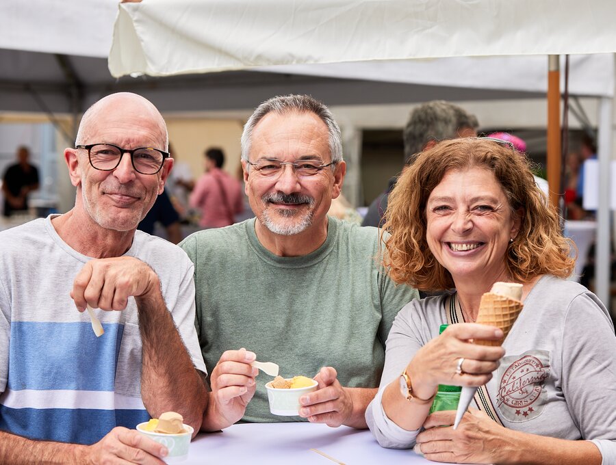 Twee mannen en een vrouw genieten samen van een ijsje.