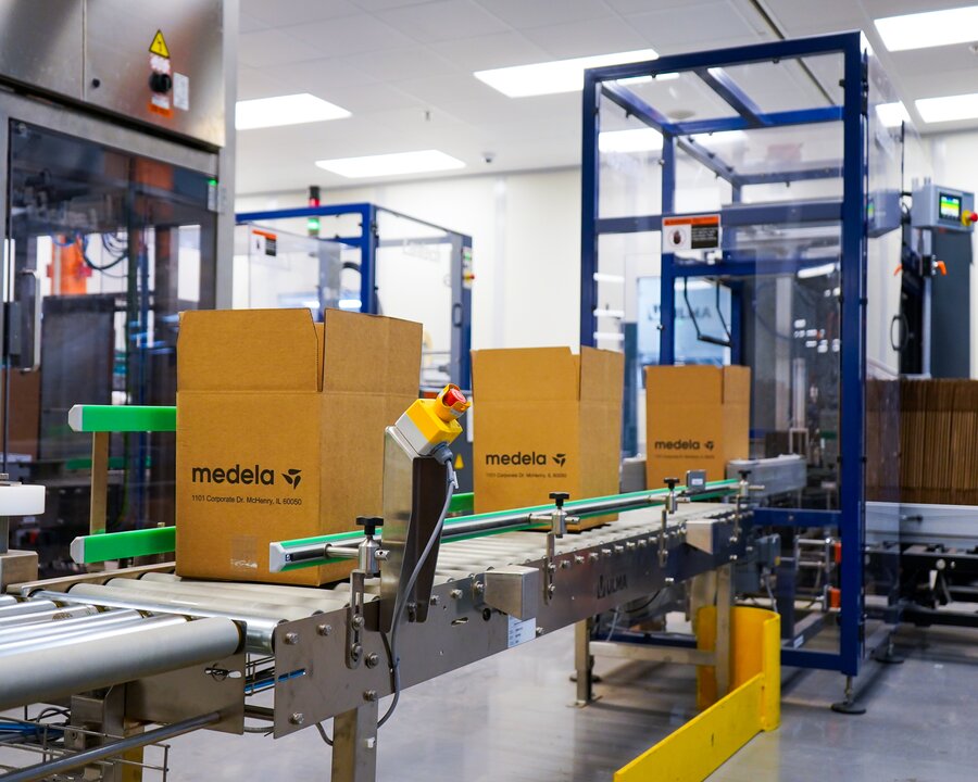 Transportbandsysteem in magazijn met dozen van Medela die erlangs bewegen.