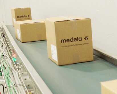 Boxes labeled "Medela" on a conveyor belt.