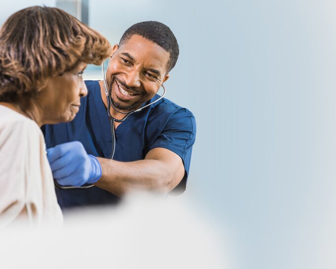 Medico che ascolta il cuore di una donna con uno stetoscopio