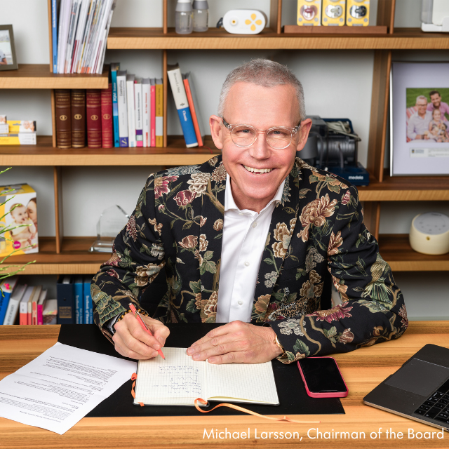 Photo of Michael Larsson signing a document while sitting at a desk.