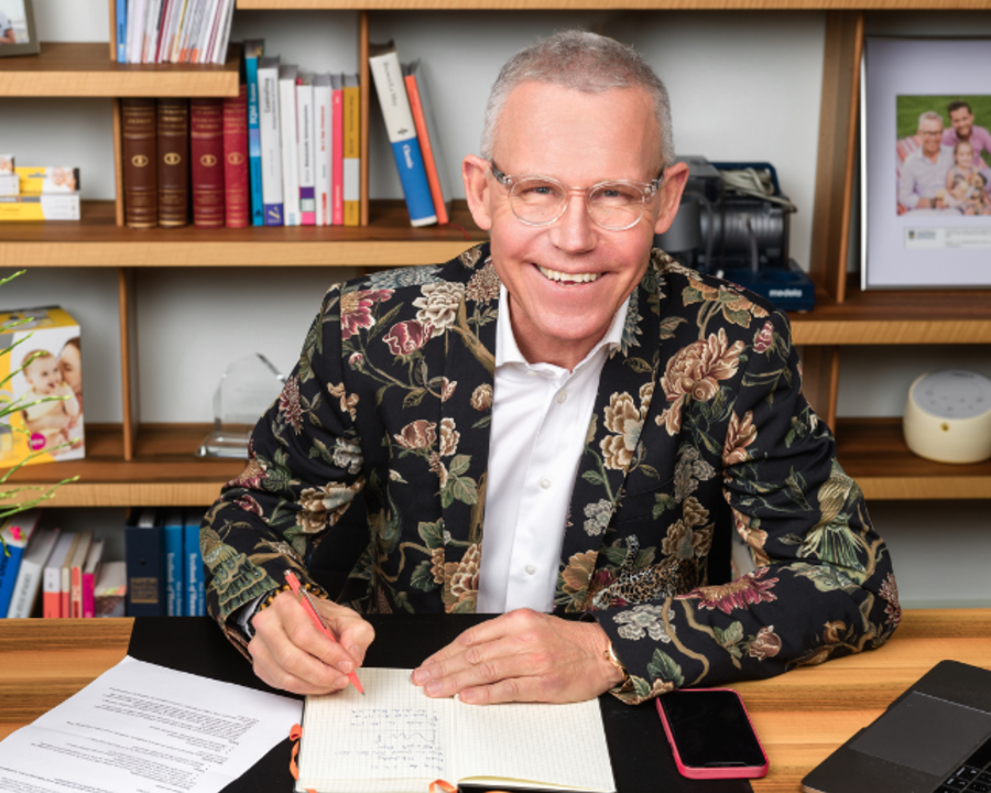 Foto van Michael Larsson die een document ondertekent terwijl hij achter een bureau zit.