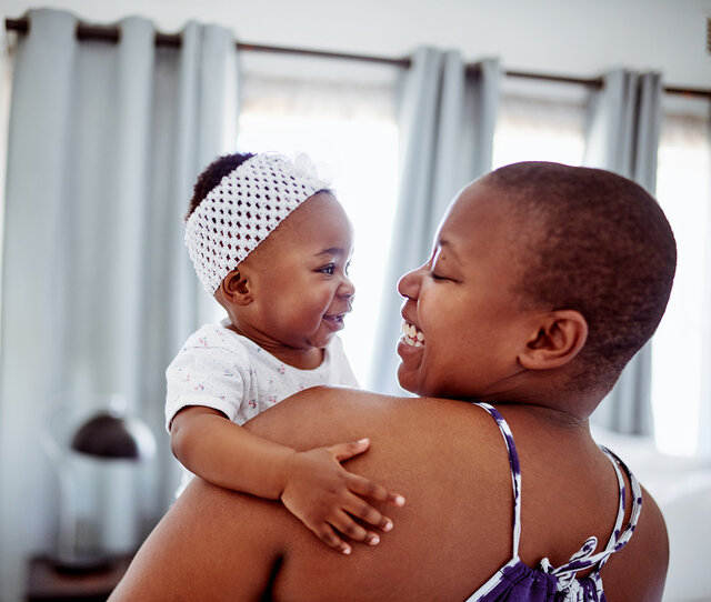 Mother holding baby and both smiling at one another