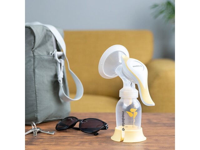 The Medela Harmony™ manual breast pump on a table at home ready to go with keys, glasses and diaper bag.