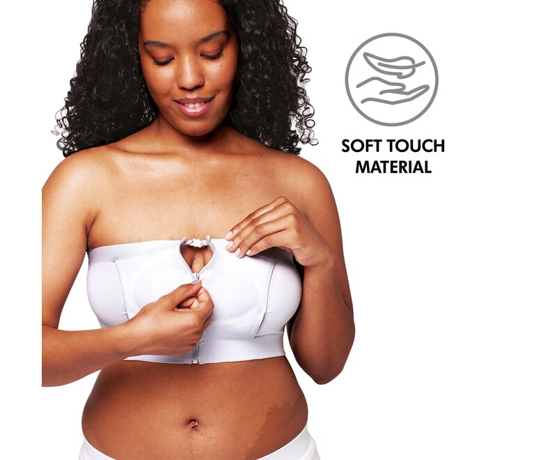Uma mulher usa um Medela Hands-free™ Pumping Bustier branco e demonstra como é fácil abrir o fecho. Inclui texto: “Material de toque suave”
