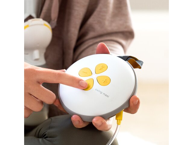 Woman pressing button on her Medela Swing Maxi™ double electric breast pump.