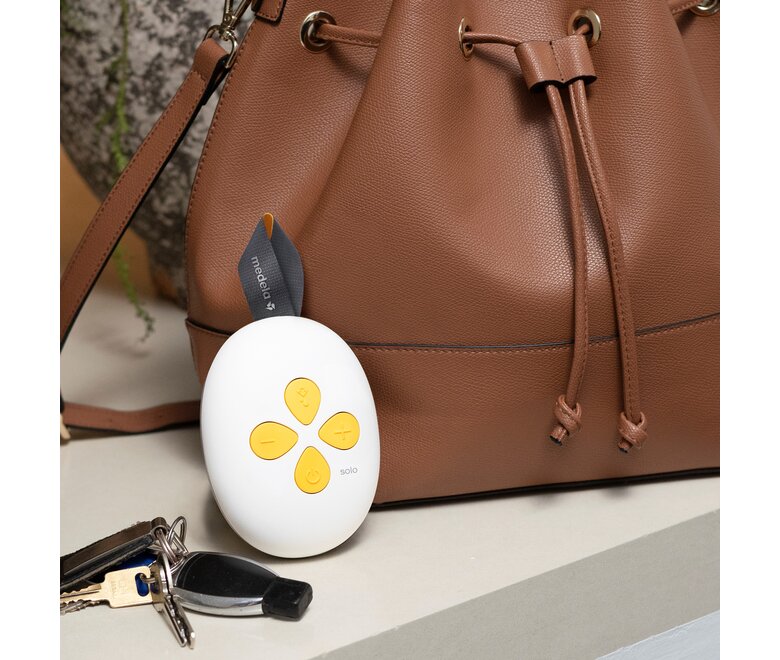 De Medela Solo™ Hands-free enkele elektrische borstkolf op het aanrecht bij mama's handtas en sleutels.