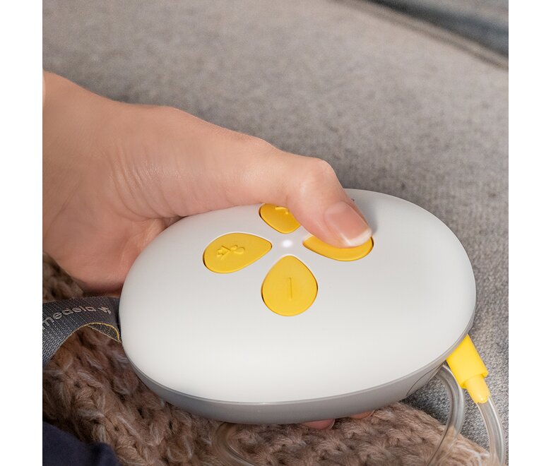 Een vrouw verandert de instellingen van haar Medela Swing Maxi™ Hands-free borstkolf.