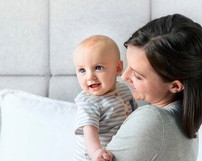 Eine Mutter hält ihr Baby, während sie beide lächeln.