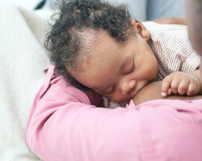 Un bambino che allatta in grembo alla mamma mentre è a casa.