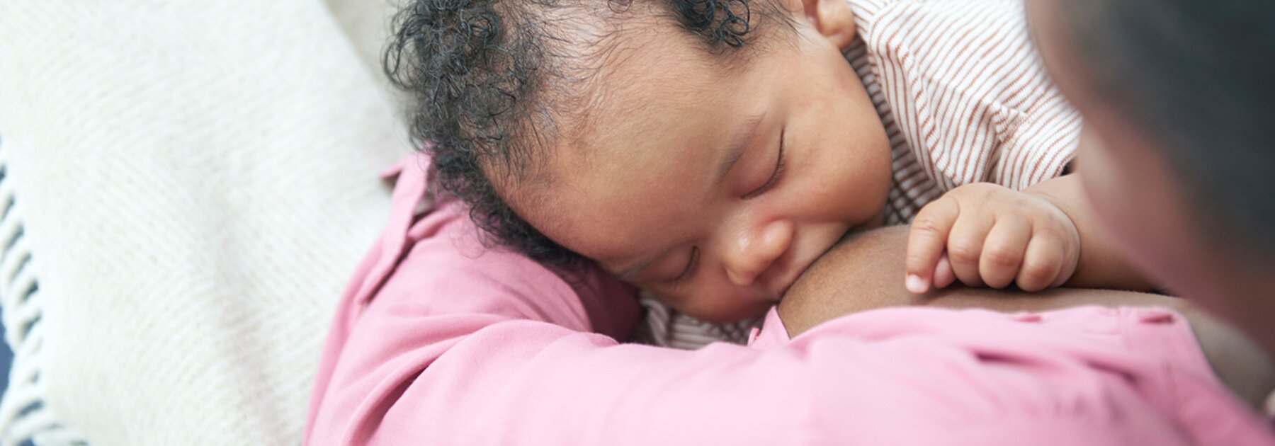 Un bambino che allatta in grembo alla mamma mentre è a casa.