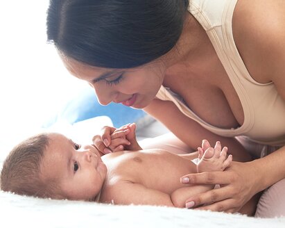 Eine Mutter spielt mit ihrem Baby auf dem Bett.